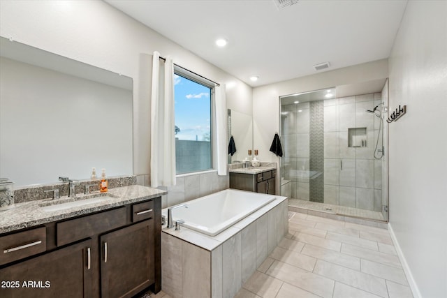 full bath with visible vents, two vanities, a stall shower, a bath, and a sink