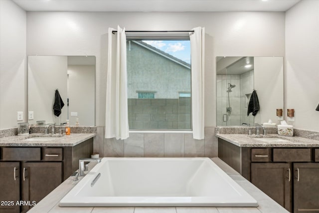 full bathroom with a stall shower, two vanities, a garden tub, and a sink