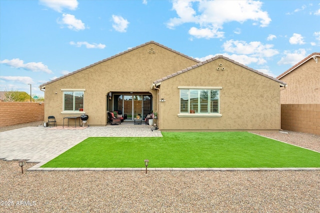 rear view of property featuring a tiled roof, stucco siding, a yard, a fenced backyard, and a patio area