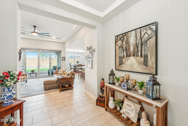 hall featuring light tile patterned floors, baseboards, and an inviting chandelier