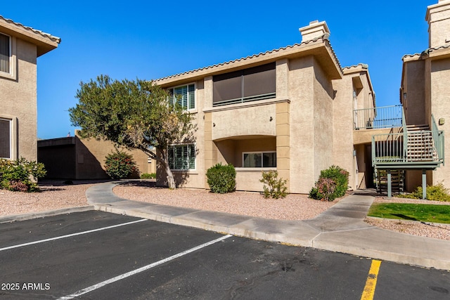 view of property featuring uncovered parking and stairway