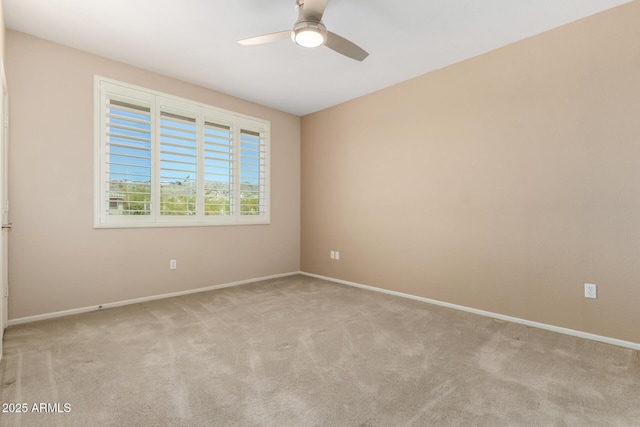 carpeted spare room featuring ceiling fan and baseboards