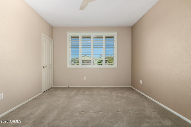 carpeted spare room with a ceiling fan and baseboards