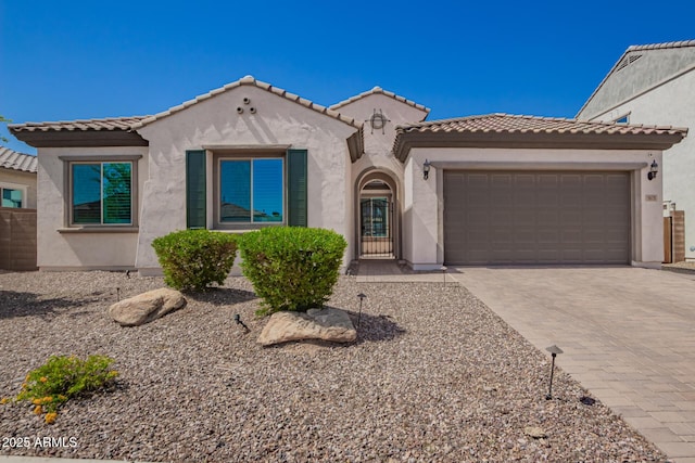 mediterranean / spanish house with stucco siding, a garage, driveway, and a tile roof
