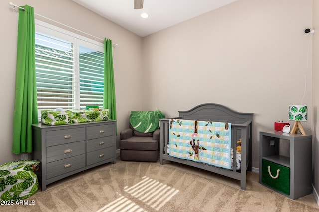 bedroom with carpet, a nursery area, and ceiling fan