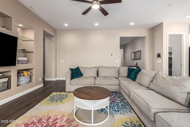 living room featuring ceiling fan, dark wood-type flooring, baseboards, recessed lighting, and built in shelves