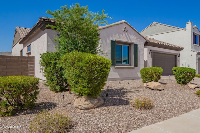 mediterranean / spanish house featuring stucco siding, an attached garage, and a tile roof