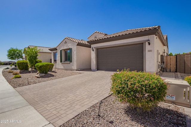 mediterranean / spanish home with stucco siding, an attached garage, driveway, fence, and a tiled roof