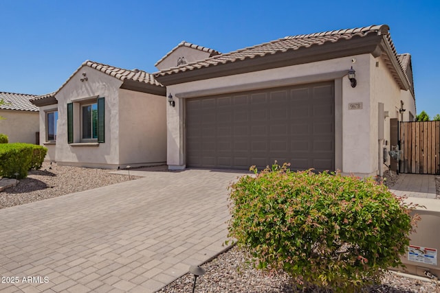 mediterranean / spanish house with stucco siding, a garage, driveway, and a tiled roof