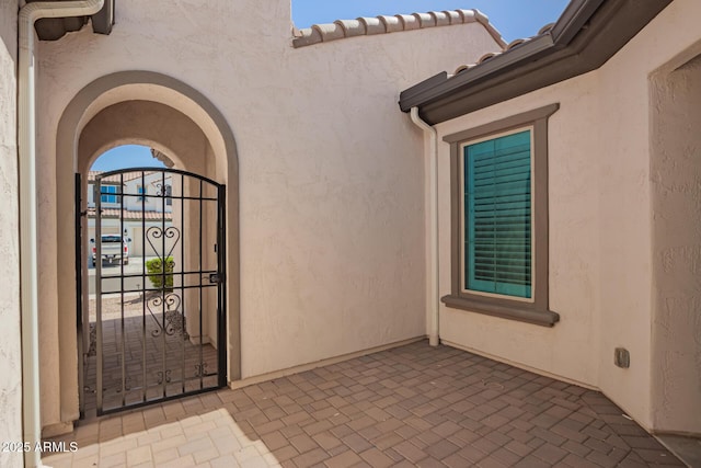 entrance to property featuring a gate and stucco siding