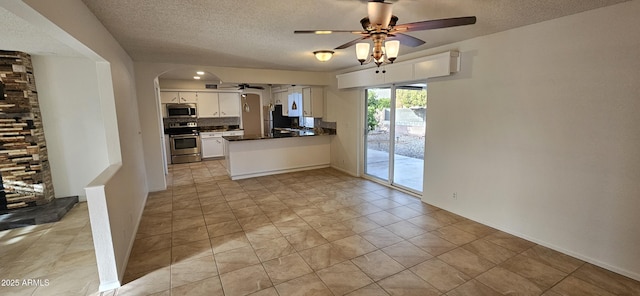 kitchen featuring a textured ceiling, kitchen peninsula, ceiling fan, stainless steel appliances, and white cabinets