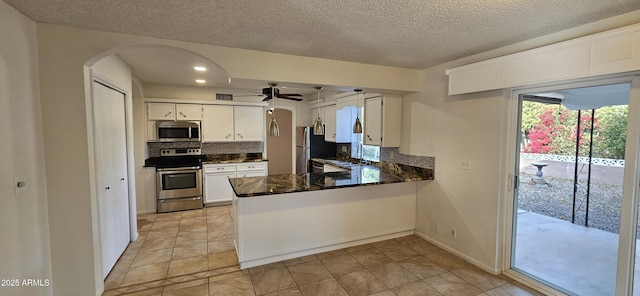 kitchen with a textured ceiling, kitchen peninsula, white cabinets, stainless steel appliances, and backsplash