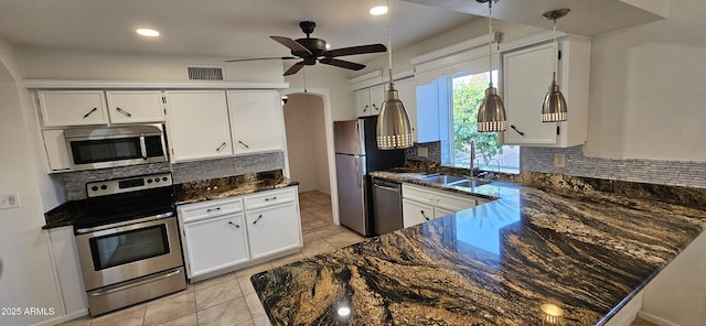 kitchen featuring sink, appliances with stainless steel finishes, dark stone countertops, white cabinets, and decorative backsplash