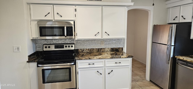 kitchen featuring white cabinetry, appliances with stainless steel finishes, light tile patterned floors, and backsplash