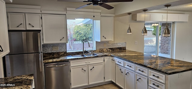 kitchen with appliances with stainless steel finishes, kitchen peninsula, sink, and white cabinets