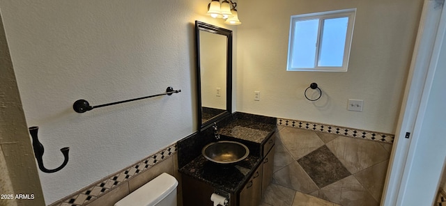 bathroom featuring vanity, toilet, and tile walls