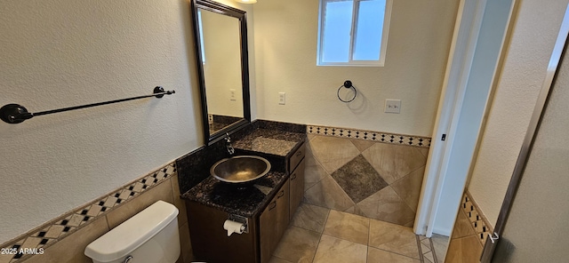 bathroom featuring vanity, tile walls, tile patterned floors, and toilet