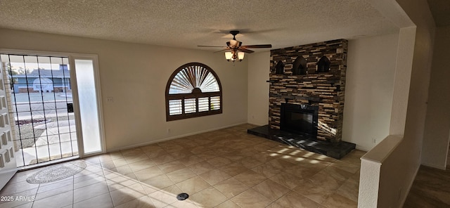 unfurnished living room featuring tile patterned flooring, ceiling fan, a stone fireplace, and a textured ceiling