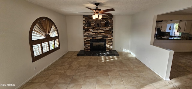 unfurnished living room featuring ceiling fan, light tile patterned floors, a fireplace, and a textured ceiling