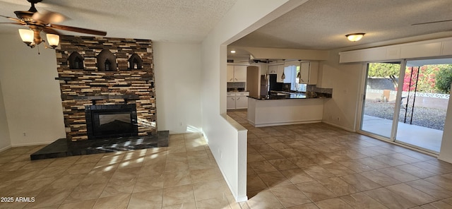 kitchen featuring white cabinetry, a fireplace, stainless steel fridge, and a textured ceiling