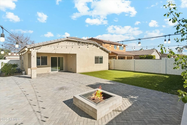 rear view of property with a patio area, a yard, and a fire pit