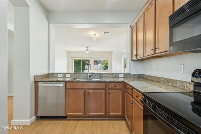 kitchen featuring light hardwood / wood-style flooring, ceiling fan, sink, stone counters, and black appliances