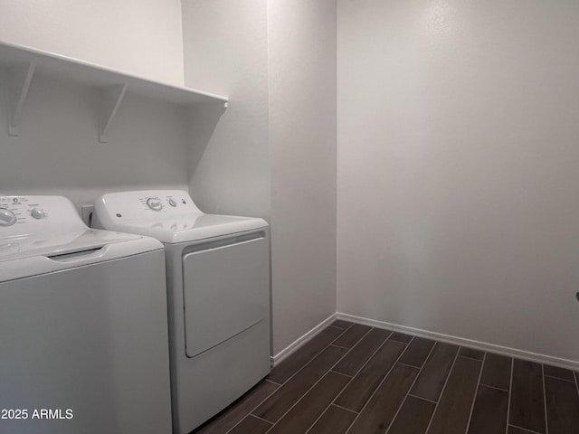 clothes washing area featuring wood tiled floor, independent washer and dryer, baseboards, and laundry area