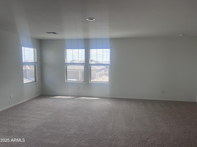 spare room featuring baseboards, visible vents, and carpet floors