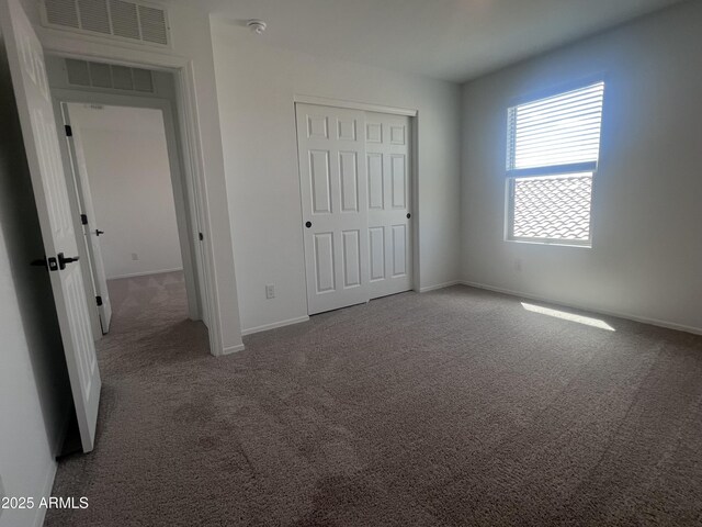 unfurnished bedroom featuring baseboards, carpet floors, visible vents, and a closet
