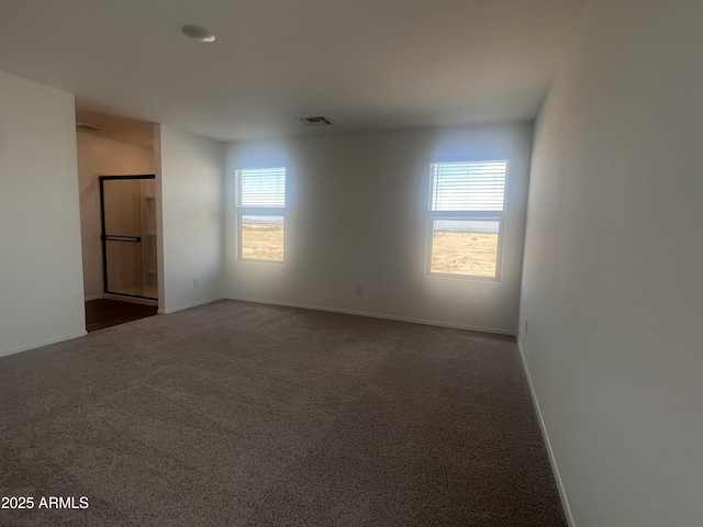 empty room featuring plenty of natural light, baseboards, and dark carpet