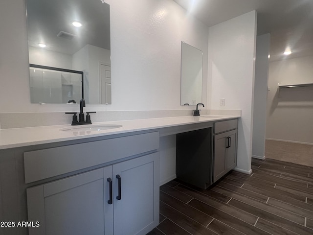 full bath with wood finished floors, a sink, double vanity, and a stall shower