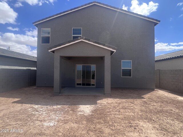 rear view of property featuring stucco siding, a patio area, a tiled roof, and fence