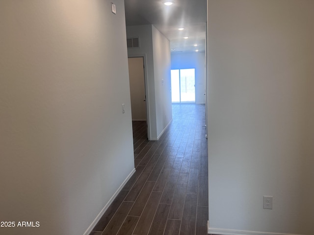 corridor featuring baseboards, visible vents, and dark wood finished floors