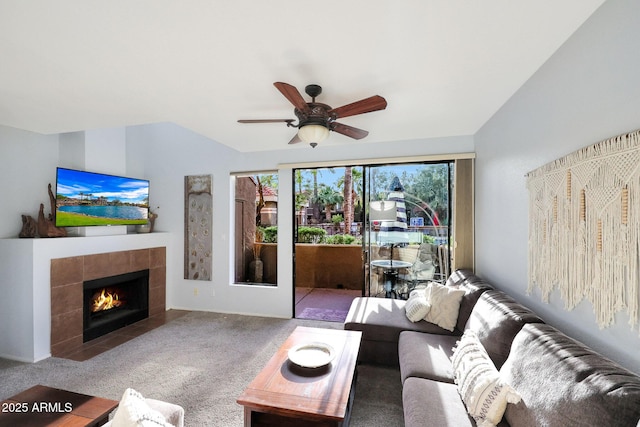 living room featuring carpet, vaulted ceiling, ceiling fan, and a tile fireplace