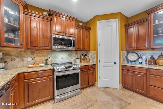 kitchen with light stone counters, stainless steel appliances, and backsplash