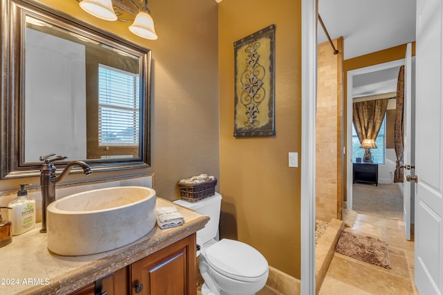 bathroom with walk in shower, vanity, and toilet