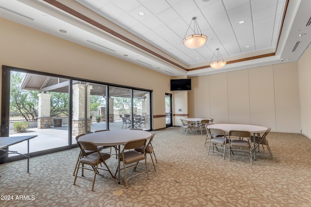 carpeted dining space with a tray ceiling