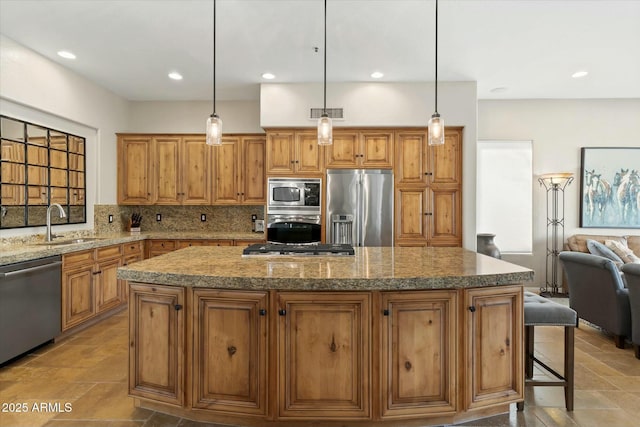 kitchen featuring backsplash, brown cabinets, appliances with stainless steel finishes, and a center island