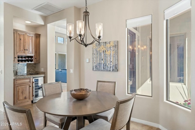 dining area with beverage cooler, visible vents, baseboards, bar area, and a chandelier