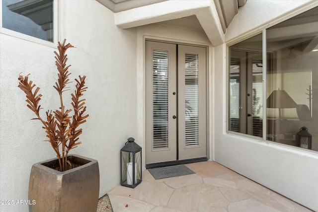 entrance to property with a patio, french doors, and stucco siding