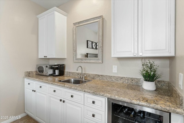 kitchen with a sink, wine cooler, light stone counters, and white cabinets