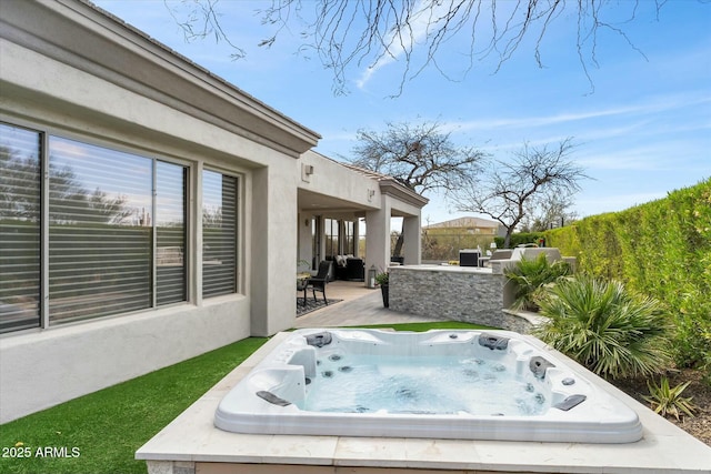 view of patio featuring an outdoor hot tub, an outdoor kitchen, and fence