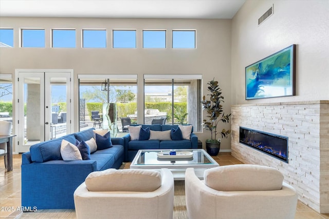 living room with light tile patterned floors, visible vents, a high ceiling, and a fireplace