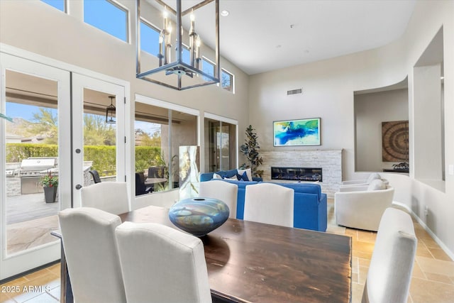 dining space featuring a stone fireplace, french doors, visible vents, and a wealth of natural light