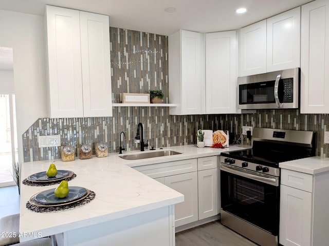 1561 N Sterling St, Mesa, AZ 85207 - kitchen with stainless steel appliances, a peninsula, decorative backsplash, white cabinetry, and recessed lighting