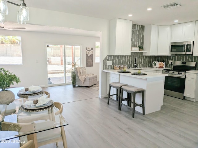 1561 N Sterling St, Mesa, AZ 85207 - kitchen with appliances with stainless steel finishes, tasteful backsplash, a kitchen breakfast bar, light countertops, and recessed lighting