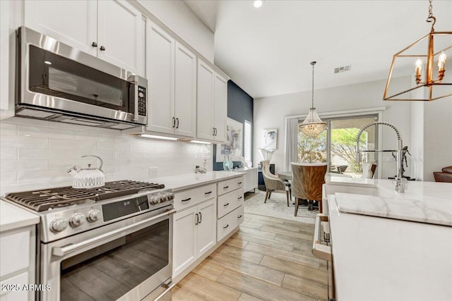 kitchen with stainless steel appliances, tasteful backsplash, visible vents, and white cabinetry