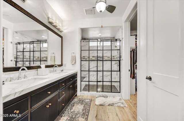 bathroom with a walk in closet, visible vents, a stall shower, and a sink