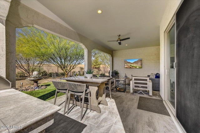 view of patio with outdoor dining space, fence, and ceiling fan