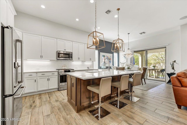 kitchen featuring decorative backsplash, white cabinets, stainless steel appliances, and light countertops